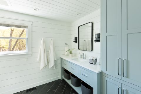 A contemporary modern bathroom design for a country home cabin. featuring a  classic freestanding vanity and linen storage cabinet.